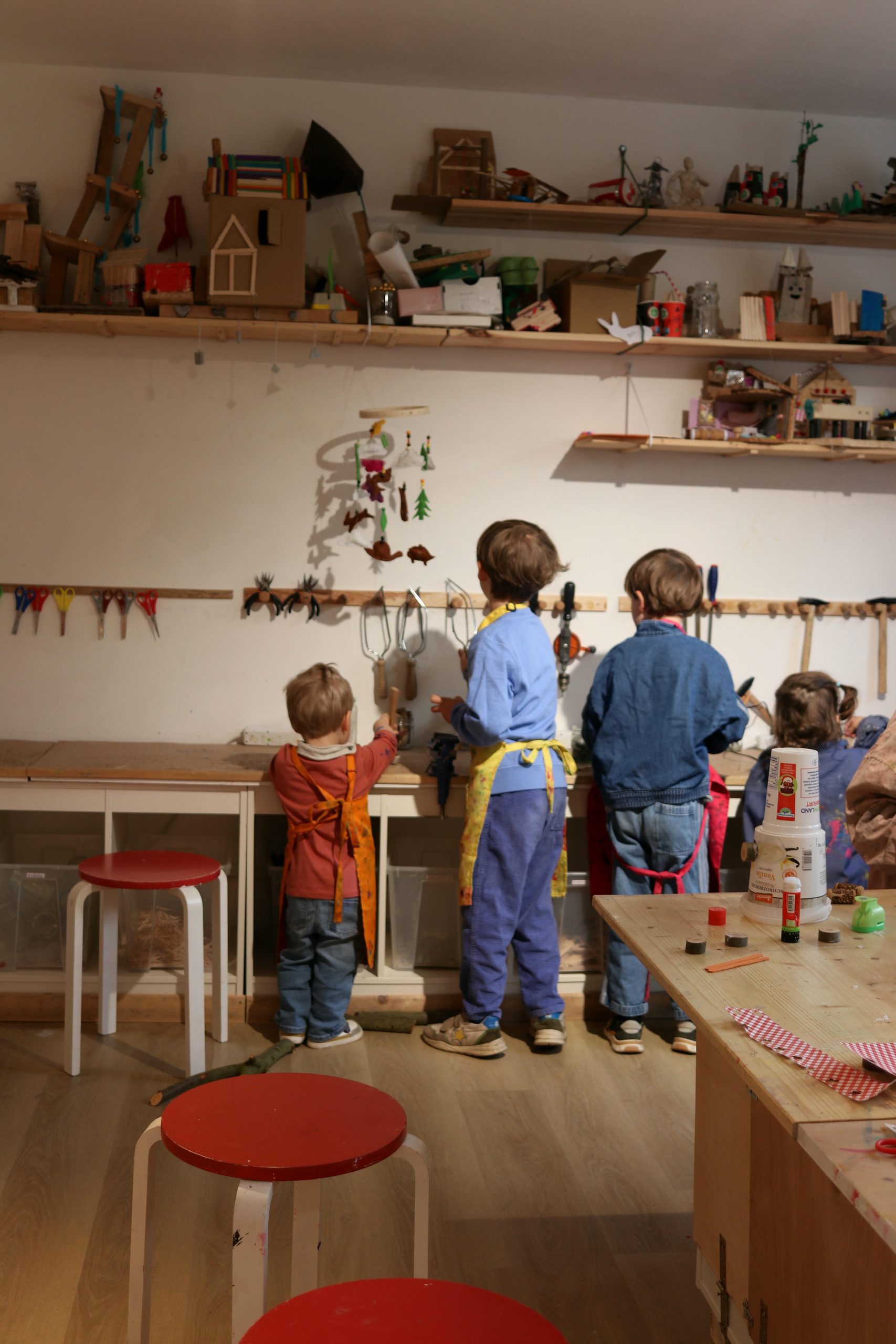 Kinder beim Werkeln und Basteln in der Kindermalwerkstatt mit Werkzeug und Bastelutensilien